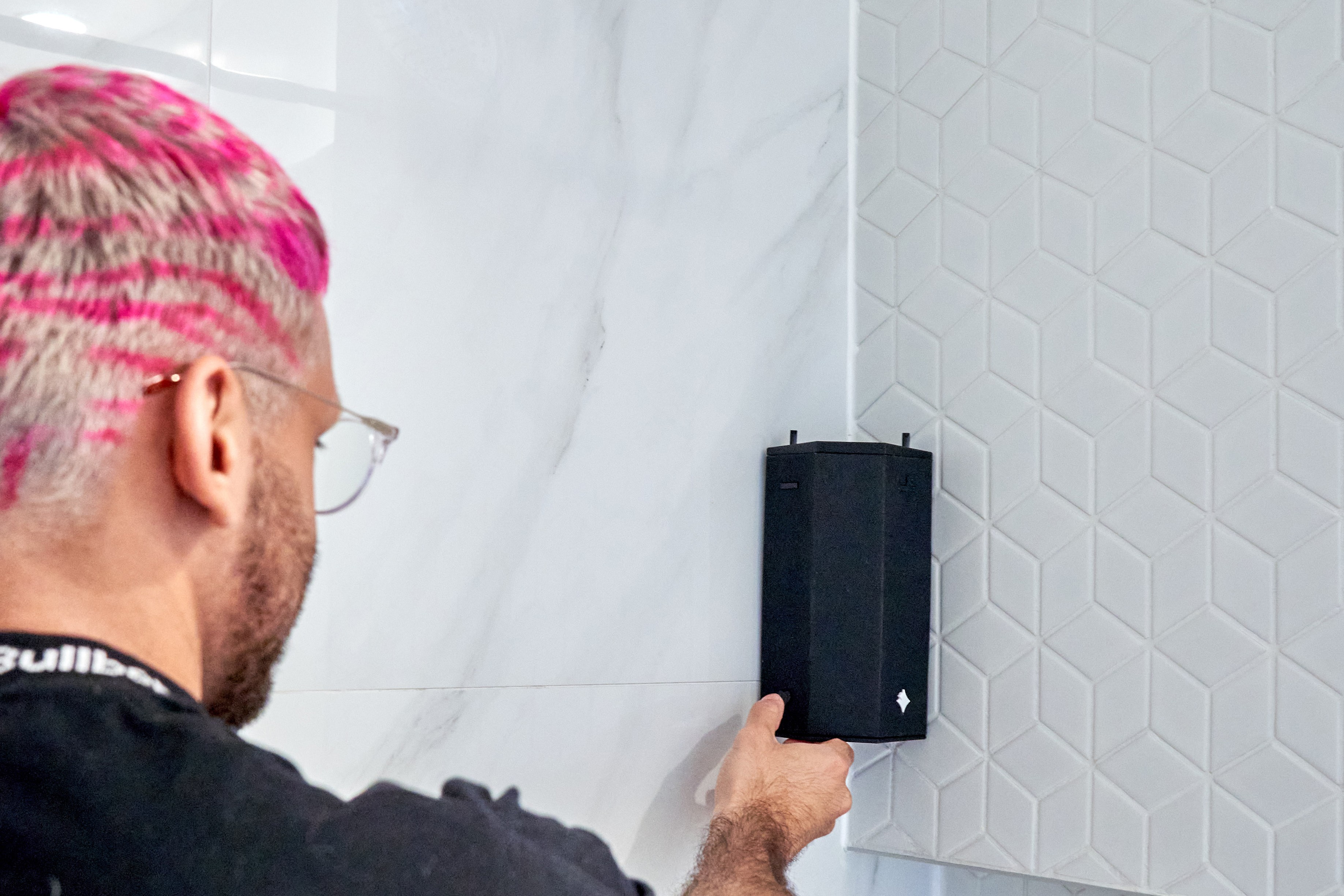 close-up image of a person's hand clicking a button on the speaker